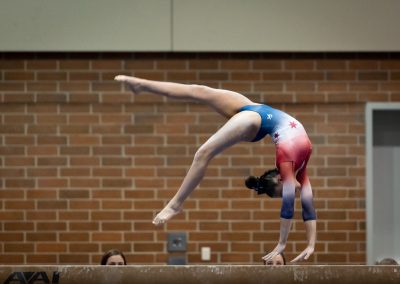 Team gymnast doing a back handspring on the beam