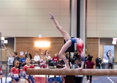 Team gymnast doing a back walkover on the balance beam